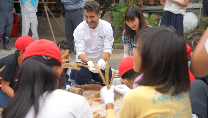 収穫、脱穀を体験するゴルカ氏と水窪小学生5年生 2