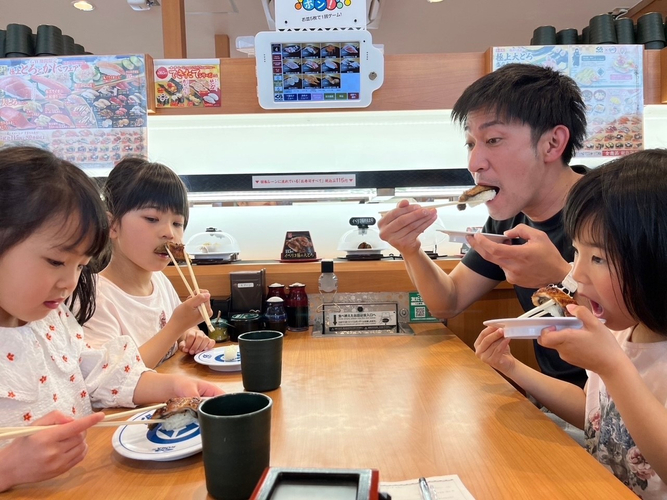 「おかやま理大うなぎ」を美味しそうにほおばる家族連れ（岡山市内のくら寿司で）